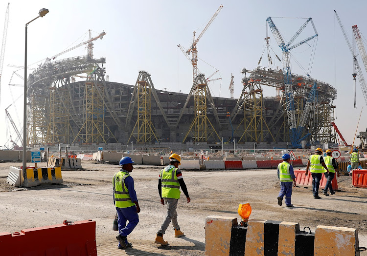 FILE PHOTO: Workers walk towards the construction site of the Lusail stadium which will be build for the upcoming 2022 Fifa soccer World Cup during a stadium tour in Doha, Qatar, December 20, 2019.  REUTERS/Kai Pfaffenbach/File Photo